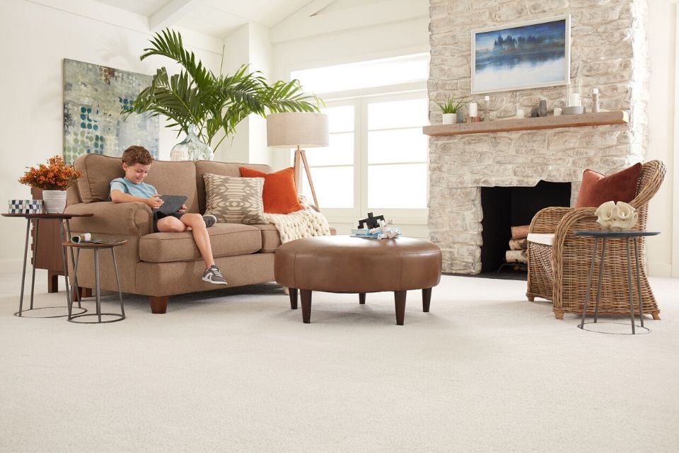 boy sits on comfy couch in living room with soft beige carpet